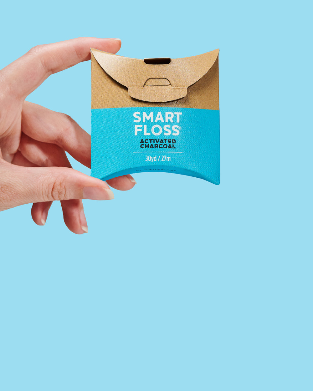 Hand holding a package of Smart Floss against a blue background